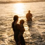 Family playing in the sea at sunset